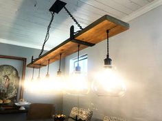 some lights are hanging from the ceiling above a table with chairs and a painting on it