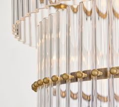 a chandelier hanging from the ceiling with glass rods and gold balls on it