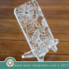 a clear card holder with flowers and leaves etched on the front, sitting on a wooden surface