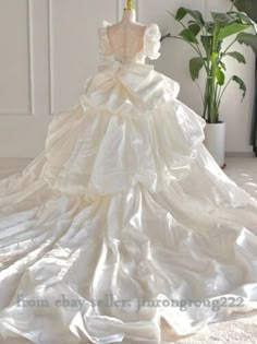 a white wedding dress on display in front of a potted plant