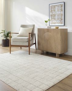 a living room with a chair, rug and sideboard in the middle of it