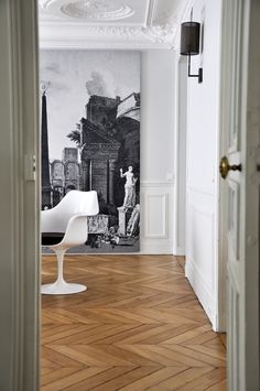 an empty room with a painting on the wall and a chair next to it in front of a doorway