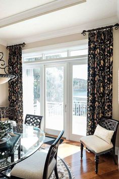 a dining room with a glass table surrounded by black and white chairs in front of a sliding glass door