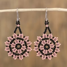 black and pink beaded earrings hanging from a wooden stick