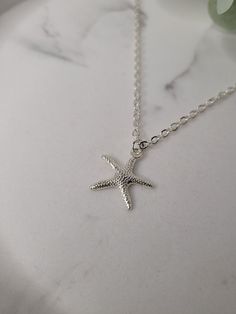 Silver plated starfish charm attached to an 18inch silver plated sparkle chain necklace with lobster claw closure. The charm is attached to the necklace via a silver plated jump ring. The charm measures 1.9cm long x 1.9cm wide. The necklace measures 18inches. This super cute starfish necklace is a great reminder of times spent near the seaside. The necklace will come gift wrapped in tissue paper and an organza bag. Please note that although I have endeavour to show of my pieces in the best, natural light, the colour may vary slightly due to screen resolution/brightness. However, if you have any questions then please feel free to message me. Dainty Starfish Charm Jewelry For Gift, Silver Starfish Jewelry As Gift, Beach Jewelry In Sterling Silver With Star Shape, Minimalist Starfish Jewelry Gift, Silver Dainty Charm Necklace 16 Inch, Beach Jewelry With Sterling Silver Star, Adjustable Necklace With Starfish Charm As Gift, Dainty Starfish Charm Jewelry Gift, Adjustable Starfish Charm Necklace As Gift