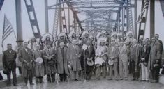 an old black and white photo of people standing on a bridge