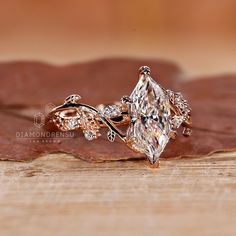 a close up view of a diamond ring on top of a leafy wooden surface