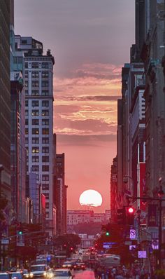 the sun is setting behind tall buildings in an urban area with traffic and people walking on the sidewalk