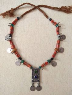 This is an old silver berber necklace from Morocco with berber pendant, coral beads,amber beads, silver berber cornerless beads, and various stones. The necklace is made with an old silver berber hirz pendant, 22 silver berber coins, 2 natural amber beads, strands of small beads of coral, old cornerless silver beads and various stones. This type of jewelry is used by women who live in the region of the Anti-Atlas of Morocco. Number of rows : 3 Measures of Hirz Pendant : 7,2 cm x 2,4 cm (2,48 inc Moroccan Necklace, Old Silver Coins, Silver Coin Necklace, Moroccan Jewelry, Carnelian Necklace, Amber Beads, Coral Beads, Coin Necklace, Coin Pendant