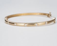 Our beautiful solid gold bezel-set diamond bangle bracelet is a timeless classic that's perfect for your wedding or anniversary, or to add as a family heirloom to your jewelry collection. It features a figure 8 locking hinge for extra security. Made with VS1 diamonds and available in 14k, 18k yellow, rose, white gold and platinum. This bracelet is fully customizable. If you prefer different size dimensions, or moissanites or colored gemstones, please contact us today to get started on a custom o Classic Yellow Gold Bangle With Diamond Accents, Yellow Gold Channel Set Diamond Bracelet, Classic Gold Bangle Bracelet With Diamond Accents, Classic Yellow Gold Diamond Bangle, Timeless Round Diamond Bracelet Channel Set, Timeless Round Diamond Bracelet With Channel Set, Timeless Round Channel Set Bracelets, Classic Bangle With Single Cut Diamonds, Classic Yellow Gold Diamond Bracelet With Channel Set