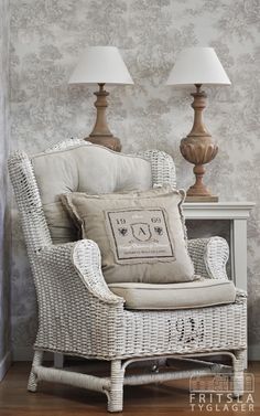 a wicker chair with two lamps on either side and a white table in the background