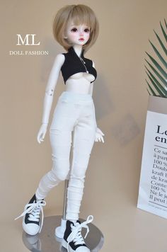 a doll is standing on top of a metal stand with white pants and black shirt