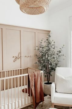 a baby's room with a crib, chair, and potted plant