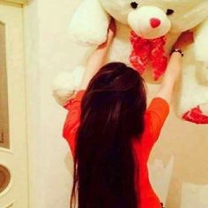 a woman is holding a large teddy bear up to the wall in front of her