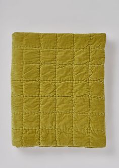 a yellow quilted blanket on a white background