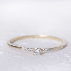 a yellow gold ring with three stones on it and a diamond in the middle, sitting on a white surface