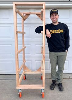 a man standing in front of a wooden shelf with wheels on the bottom and top