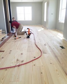 a man is working on the floor in an empty room with wood floors and drywalls