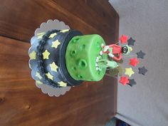 a green and black cake with stars on it sitting on top of a wooden table