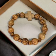 "Handcrafted in the Holy Land, our Olive Wood Bracelet is a truly unique piece of jewelry. Made from high-quality olive wood, this bracelet features a cross pendant adorned with olive wood bead.  -The word \"Jerusalem\" is engraved on one side. -Versatile and suitable for both men and women, this bracelet makes for a meaningful gift for any age. - With its natural beauty and spiritual significance, wearing this Olive Wood Bracelet is like carrying a piece of the Holy Land with you wherever you g Natural Wood Round Beads Bracelet Gift, Gift Natural Wood Round Bead Bracelets, Gift Natural Wood Round Beads Bracelet, Natural Wood Beaded Bracelets As Gift, Natural Wood Beaded Bracelet As Gift, Natural Wood Beaded Bracelets For Gifts, Wooden Bracelets With Round Beads For Gifts, Wooden Beaded Bracelets For Gifts, Natural Wood Bracelet Jewelry Gift