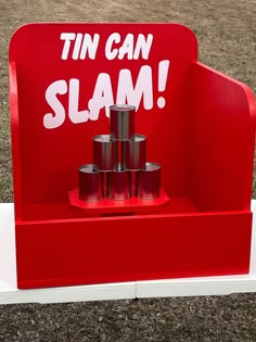 a red sign that says tin can slam on it's stand with some cans in it