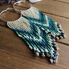 a close up of a necklace on a wooden table with beads and silver hoop earrings