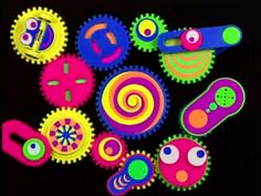 an assortment of different colored gears on a black background, with eyes and nose shapes