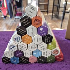 there is a pyramid made out of different types of boxes on the floor in front of a purple carpet