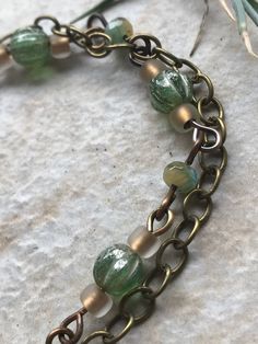 This bracelet was made by me in my studio, including the ceramic focal bead. It is glazed on both sides, though it definitely has a "front" and "back," as it is curved to fit the wrist. The wire and clasp are antique brass. This bracelet has a stacked or layered look, with multiple strands. The bracelet is 9 inches long and is adjustable to 7.75 inches. It weighs 18 grams. An average fork weighs 35 grams, and a Sharpie marker weighs 9 grams if you need a reference. All items are one of a kind - Brass Beaded Bracelets With Round Beads, Brass Bracelets With Round Beads As Gift, Brass Bracelets With Round Beads For Gifts, Unique Metal Beaded Bracelets With Round Beads, Handmade Spiritual Brass Beaded Bracelets, Unique Beaded Brass Bracelets, Unique Beaded Brass Bracelet, Handmade Bronze Jewelry With Czech Glass, Handmade Czech Glass Bronze Jewelry