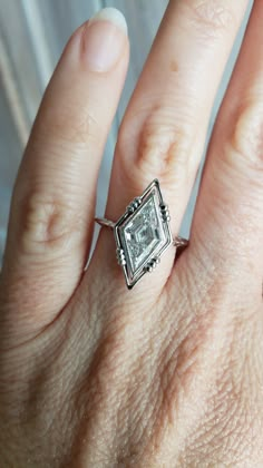 a woman's hand with a diamond ring on top of her left hand,