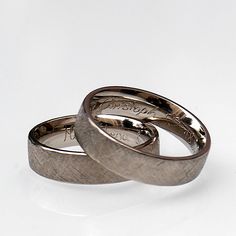 two silver wedding rings sitting on top of each other