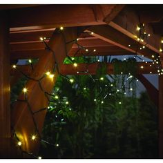 a wooden structure with lights hanging from it's sides and trees in the background