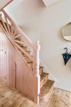 a wooden stair case next to a mirror on the wall