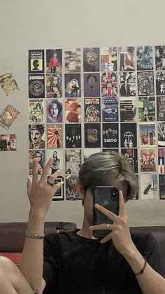 a person taking a selfie in front of a wall covered with posters and stickers