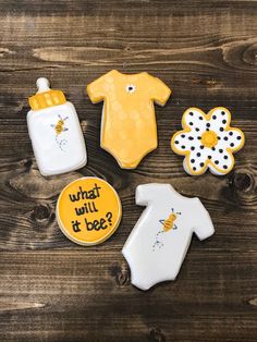 baby shower cookies and bodysuits are on a wooden table with the words what will it bee?