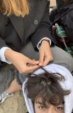 a person cutting another persons hair with scissors