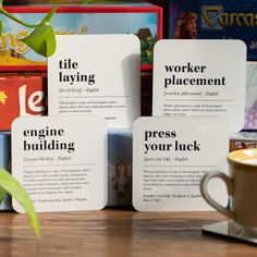 three cards with words on them sitting next to a cup of coffee and some books