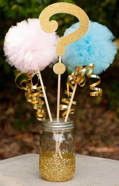 a mason jar filled with cupcake toppers next to a gold and blue question mark