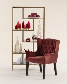 a red chair sitting in front of a book shelf filled with christmas trees and ornaments