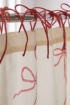 the curtains are red and white with designs on them, hanging in front of a window