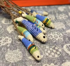 three crocheted fish ornaments sitting on top of a blue and white table cloth