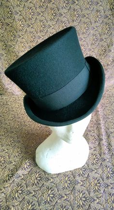 "Victorian style top hat in merinos wool, dome h 12 cm, brim 5 cm, outer band in black cotton h 4 cm, interior lined in white satin, internal sweatband in soft black leather. Entirely hand-made and sewn, the wing has the typical \"curl\" with the grosgrain finish sewn and turned used for the top hats and bowler hats of the 19th century." Winter Derby Felt Hat With Flat Brim, Black Formal Boater Hat With Flat Brim, Formal Black Boater Hat With Flat Brim, Curved Brim Formal Costume Hats For Winter, Formal Curved Brim Costume Hat For Winter, Curved Brim Felt Hat For Derby And Winter, Elegant Felt Hat For Derby In Winter, Formal Winter Costume Hat With Curved Brim, Winter Derby Felt Hat With Curved Brim