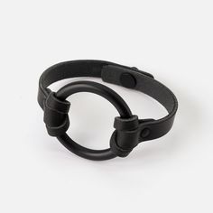 a black leather bracelet with an o - ring on the clasp and two holes in the middle