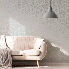 a white couch sitting next to a lamp on a wall