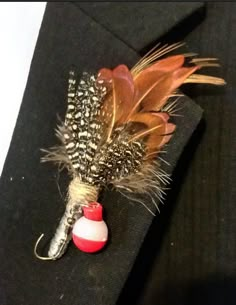 a boutonniere decorated with feathers and beads on a black piece of cloth