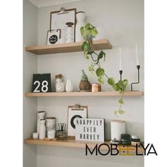 three wooden shelves with plants, candles and pictures on them in the corner of a room