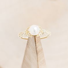 a white pearl sits on top of a piece of wood