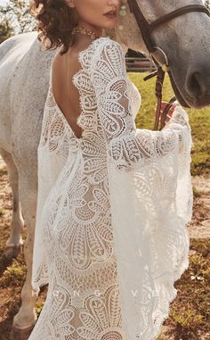 a woman in a white dress standing next to a horse