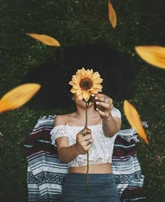 a woman holding a sunflower in front of her face