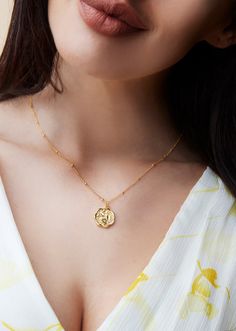 a woman wearing a gold necklace with the word love written on it and a heart charm